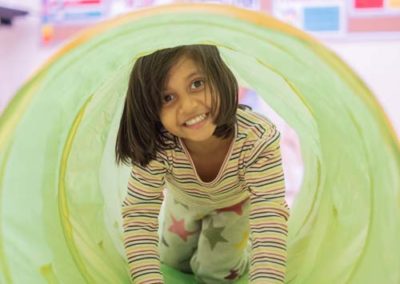 A young girl crawling through a tube.