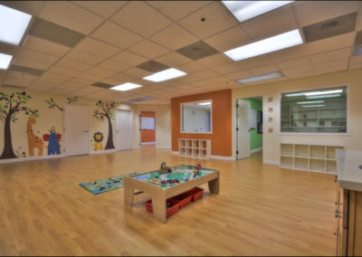 A large room with walls painted with animals and a toy table in the center.