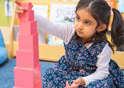A girl builds a tower with pink blocks