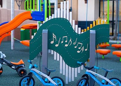 An outdoor play area with a large playground and tricycles.