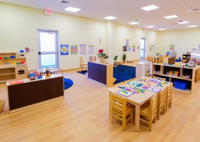 A large classroom with tables, bookshelves, and a play area.