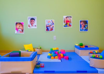 A toddler play area with mega bloks, cushioned floors, and pillows.