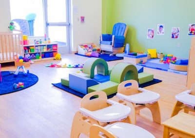A toddler-friendly play room with high chairs, toys, and rubber ramps.