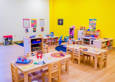 A classroom with tables, bookshelves, and a play area.