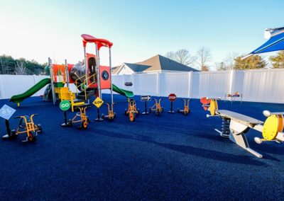 A play area with blue, rubber flooring, tricycles, and a playground.