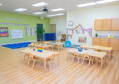A large classroom with group tables, learn materials, and art supplies.