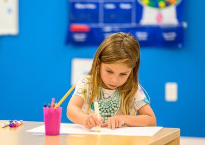 A young girl draws with a marker.