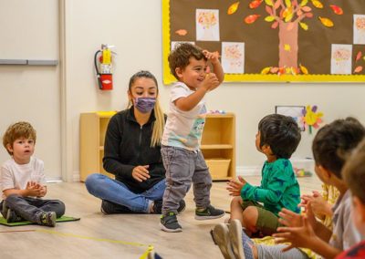 A teacher playing with toddlers in a game.