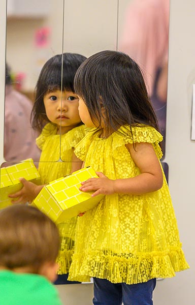 A young girl in a yellow dress while holding a yellow box.