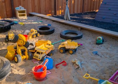 An outdoor sandbox with many toys and digging materials.
