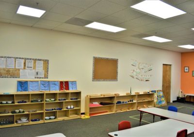 A Safari Kid classroom with wooden bookcases, wall decorations, anda large group table.