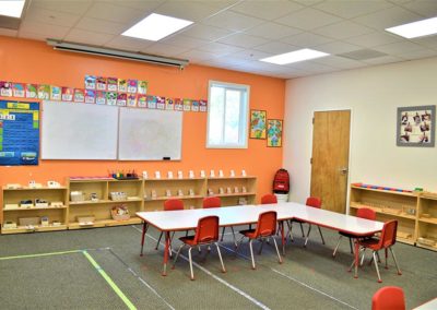A Safari Kid classroom with wooden bookcases, whiteboards, and a large group table.