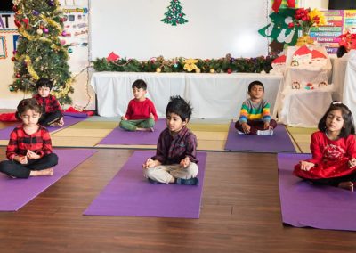 Young children meditating in a classroom decorated for Christmas.